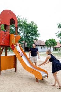 a woman playing on a slide in a playground at Ceglédi Apartmanpark & Kemping in Cegléd