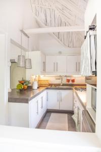 Villa Coconut Oasis في Bain Boeuf: مطبخ به دواليب بيضاء وفواكه على الكاونتر