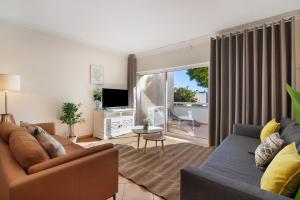 ein Wohnzimmer mit Sofa und Fernseher in der Unterkunft 1G Apt Rosmaninho in Santa Luzia