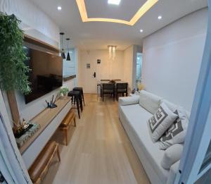 een woonkamer met een witte bank en een tafel bij Riocentro, Projac, Parque Olímpico, apartamento completo com vaga! in Rio de Janeiro