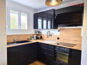 a kitchen with black cabinets and a sink at Le Fit and Chill - Confort & Calme - Parking - Proche Aéroport et Plage du Jaï in Marignane
