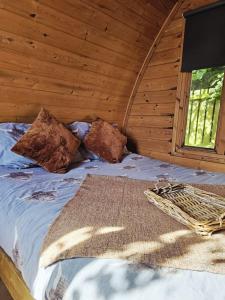 The Forest Pod - Wood Fired Hot Tub and Fire Pit في Hambleton: سرير في كوخ خشبي به نافذة