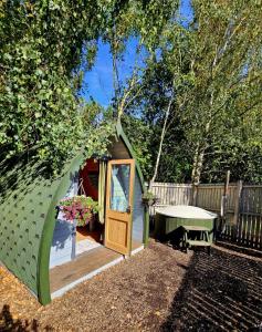 The Forest Pod - Wood Fired Hot Tub and Fire Pit في Hambleton: خيمة خضراء صغيرة ذات باب في فناء