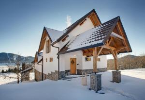 a house with a snow covered roof in the snow at Komforna planinska kuća za odmor in Mrkopalj