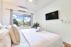 a bedroom with a white bed and a flat screen tv at Style, Luxury and Comfort in Larrakeyah in Larrakeyah
