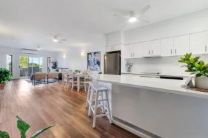 a kitchen with white cabinets and a dining room at Style, Luxury and Comfort in Larrakeyah in Larrakeyah
