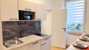 a kitchen with white cabinets and a sink and a microwave at M8 ParkSide Studio One in Graz