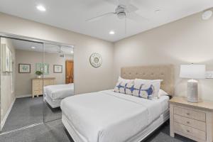 ein Schlafzimmer mit einem großen weißen Bett und einem Spiegel in der Unterkunft Hawaiian Style Beachfront on Beach Road in Capistrano Beach