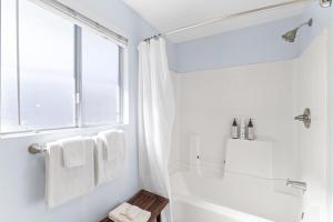 ein weißes Badezimmer mit Badewanne und Fenster in der Unterkunft Hideaway B Walk to the beach Downtown AC in San Clemente + 22 Fotos