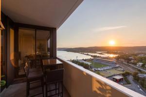 Waterfront Apartment in the Heart of Gosford في جوسفورد: بلكونة مطلة على النهر والغروب