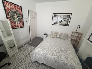 ein Schlafzimmer mit einem Bett und einem Poster an der Wand in der Unterkunft Cozy and Convenient Raynes Park maisonette in Raynes Park