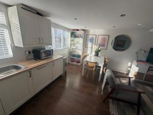 eine Küche mit weißen Schränken und einem Tisch und Stühlen in der Unterkunft Cozy and Convenient Raynes Park maisonette in Raynes Park + 9 Fotos