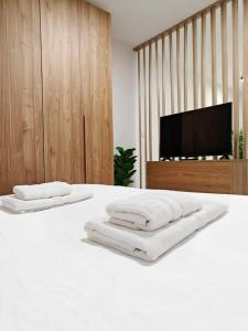 een slaapkamer met een wit bed en een flatscreen-tv bij Balluta Bliss in Il-Gżira