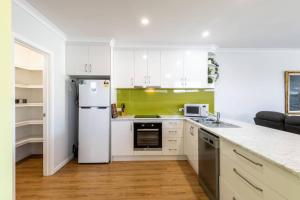 a kitchen with white cabinets and a white refrigerator at Central Chic- Beautifully appointed townhouse in Myrtleford