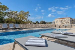 a pool with tables and chairs next to a building at Vamos villa in Vamos