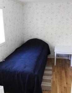 Two cottages by the forest & sea SE09136 في Slussen: غرفة نوم بسرير أزرق وطاولة