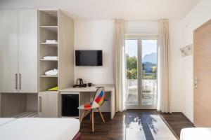 a bedroom with a bed and a desk with a chair at Hotel Villa Claudia in Nago-Torbole