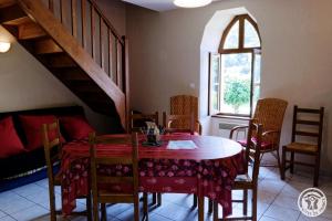 a dining room with a table and chairs and a staircase at Presbytere in Soursac