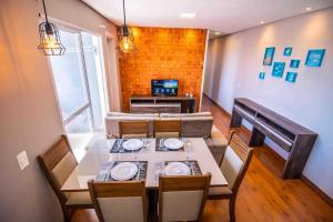 ein Esszimmer mit Tisch und Stühlen und einem Fernseher in der Unterkunft Confortável AP próximo ao parque e praias in Penha