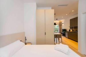 a bedroom with a white bed and a kitchen at Stancia Benimaclet - Studio 9 in Valencia