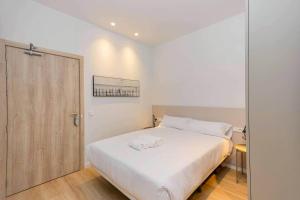 a bedroom with a white bed and a wooden door at Stancia Benimaclet - Studio 9 in Valencia +13 photos