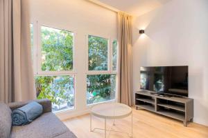 a living room with a couch and a tv and windows at Stancia Benimaclet - Studio 1 in Valencia