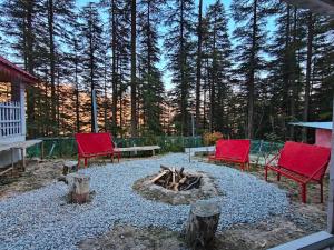 two red chairs and a fire pit in a yard at Mistymountaincottage in Shimla