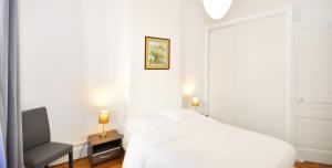 a white bedroom with a bed and a chair at Appart' Rousseau in Lyon