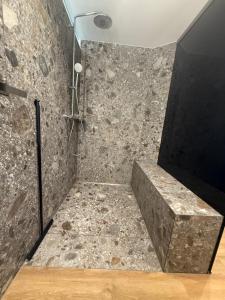 een douche met een stenen muur en een televisie bij Ferienwohnung Zwischenzeit in Kranenburg