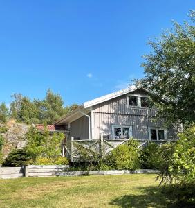 Lovely Cottage near the Resort Nösund SE09111 في Tegneby: منزل رمادي اللون محاط بسياج في فناء أمامي