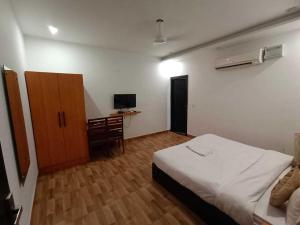 a bedroom with a bed and a cabinet and a television at Hotel O Sector 18 Dhaliawas Crossway Rewari Formerly Ignis in Rewāri