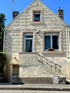 a white building with two windows and a staircase at le gîte de Léon in Saint-Pol-de-Léon