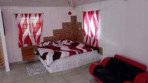 Cerroazulfarmlodge في سيرو أزول: غرفة نوم بسرير والستائر حمراء وبيضاء