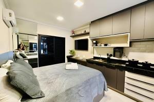 um quarto com uma cama grande e uma cozinha em Studio Ônix - A poucos passos da Ufu. em Uberlândia