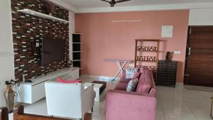 ein Wohnzimmer mit zwei Sofas und einem Flachbildfernseher in der Unterkunft Hoysala Ace 1 in Bangalore + 7 Fotos