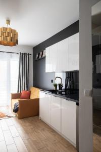 a kitchen with white cabinets and a couch at Wyjątkowy apartament z prysznicem pośrodku na wyjątkowe wieczory in Łódź