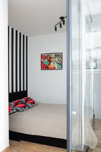 a bedroom with a bed and a picture on the wall at Wyjątkowy apartament z prysznicem pośrodku na wyjątkowe wieczory in Łódź