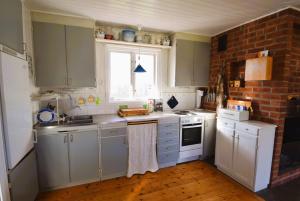 una cocina con armarios blancos y una pared de ladrillo en Two charming cottages in Hälleviksstrand SE09133, en Hälleviksstrand