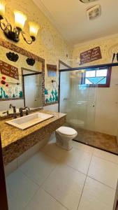 ein Badezimmer mit Toilette, Waschbecken und Spiegel in der Unterkunft Hospedagem Oxê in Paraty