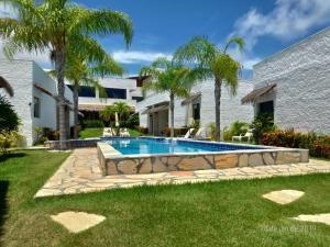 a backyard with a swimming pool and palm trees at Oasis Tajaja Pousada Boutique na Costa do Conde in Jacumã
