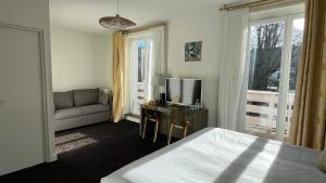 Un dormitorio con una cama, un sofá y un televisor. en Hôtel La Réserve, en Gérardmer