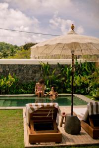 two people sitting in a swimming pool with an umbrella at Irama Surf Villas - Private Pool Villas at Yoyos in Sekongkang