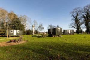 a group of tiny houses in a grass field at Ormesby Manor House & The Shepherds Huts & Well Lodge in Ormesby Saint Michael