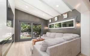 sala de estar con sofá grande y ventanas en Charming Four-Bedroom Coastal Retreat Near Neptune Beach, en Neptune Beach 1 foto más