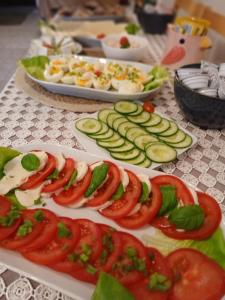 a table topped with plates of food with tomatoes and cucumbers at Pensjonat Magdalena - w cichym i spokojnym miejscu - zwierzęta akceptowane, bezpłatny parking in Szklarska Poręba +78 photos