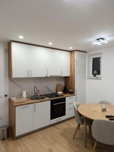 a kitchen with white cabinets and a wooden table at Bella Vacanza Apartment in Banja Luka