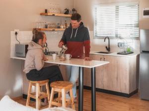 a man and woman in a kitchen preparing food at Barn Owl Cabin at Vrolikheid Landgoed in Tulbagh