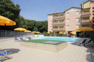 a swimming pool with chairs and umbrellas next to a building at Bright flat in Rosolina with shared pool in Rosolina Mare