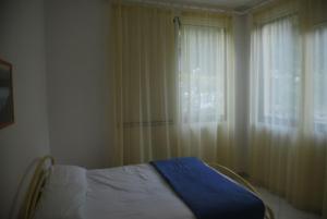 een slaapkamer met een bed en een raam met gordijnen bij Bright flat in Rosolina with shared pool in Rosolina Mare