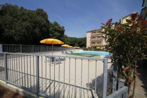 a swimming pool with umbrellas and chairs and a building at Bright flat in Rosolina with shared pool in Rosolina Mare